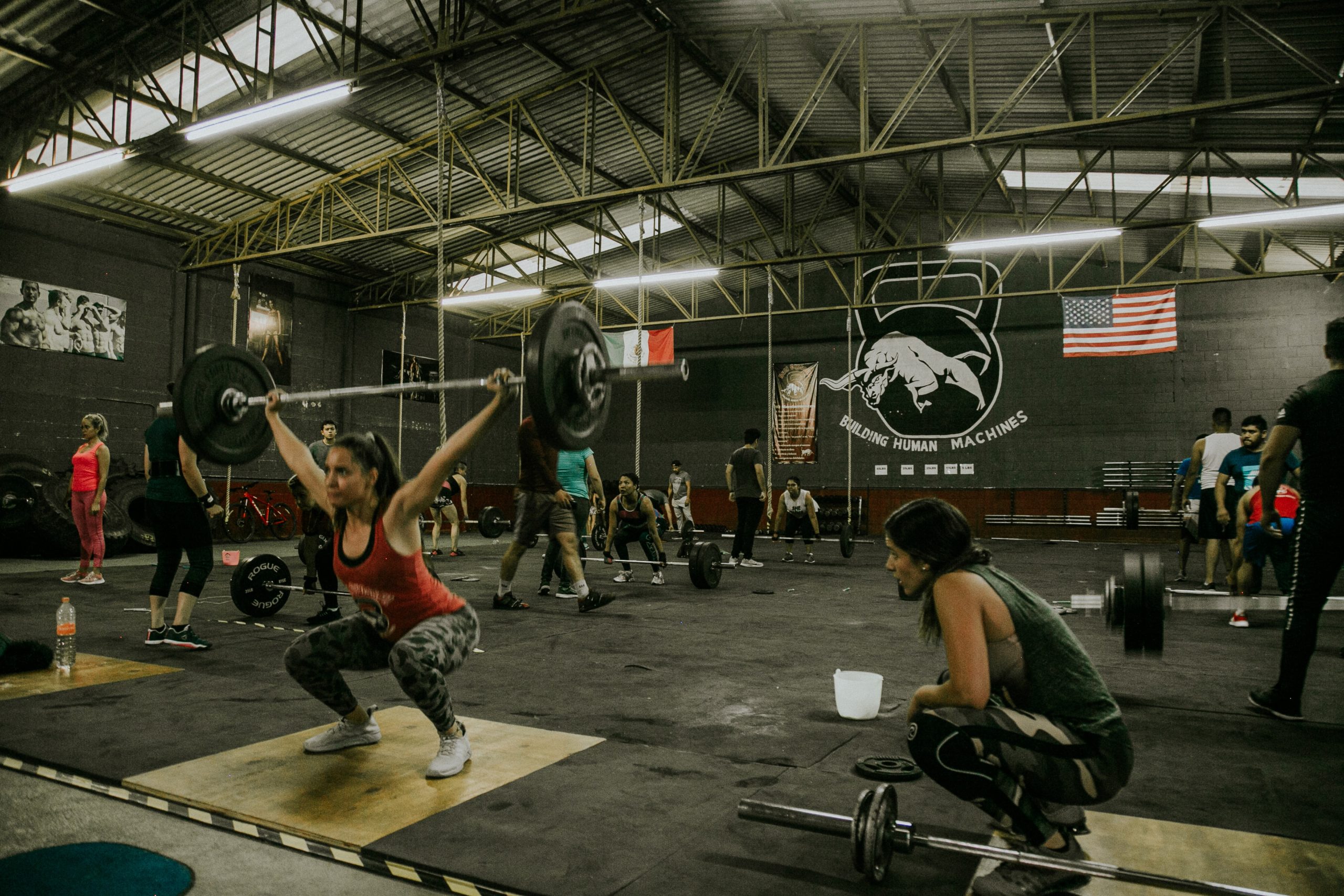 A woman powerlifting while another woman watch her stance