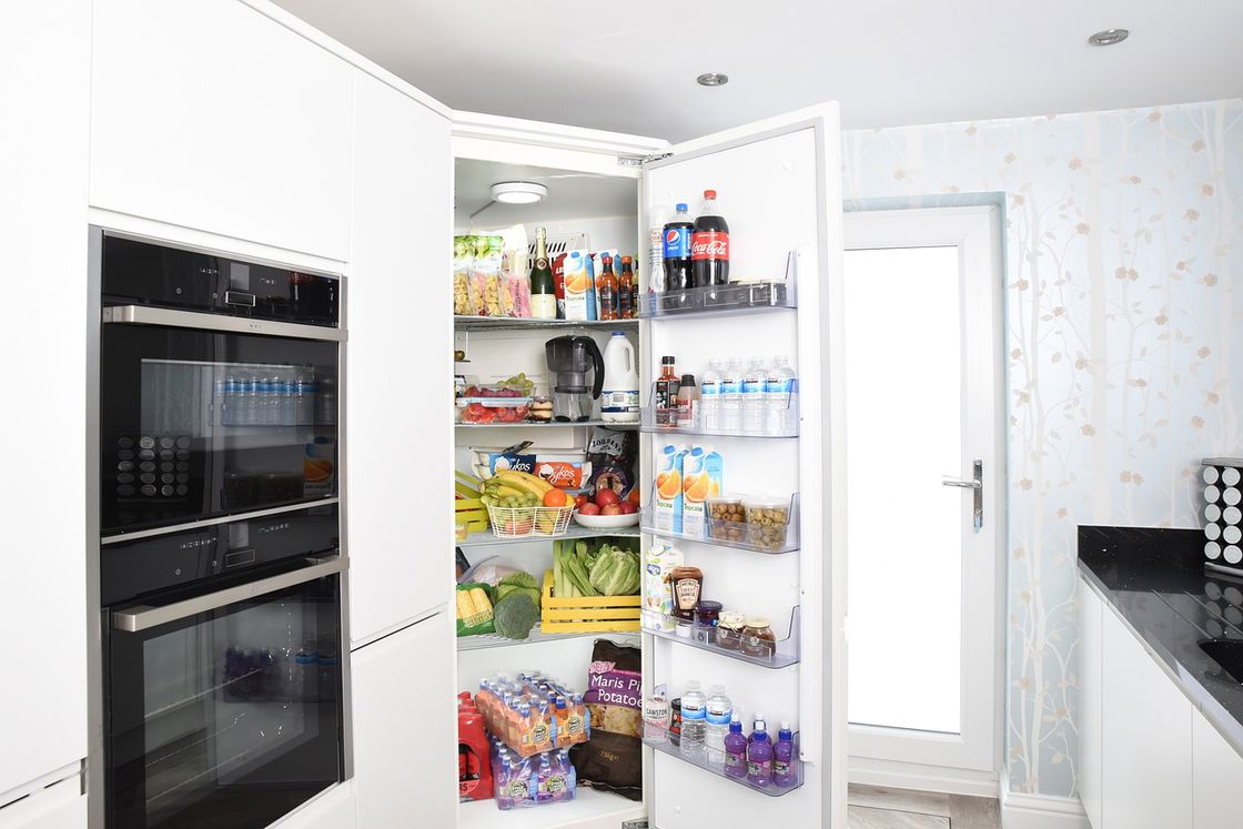 White opened refrigerator filled with fruits, sodas, water, and condiments