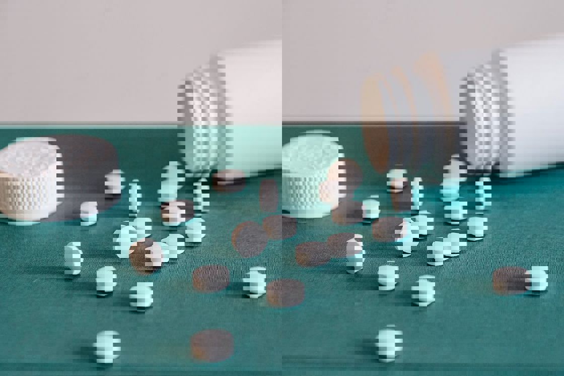 White pills spilling from a white bottle