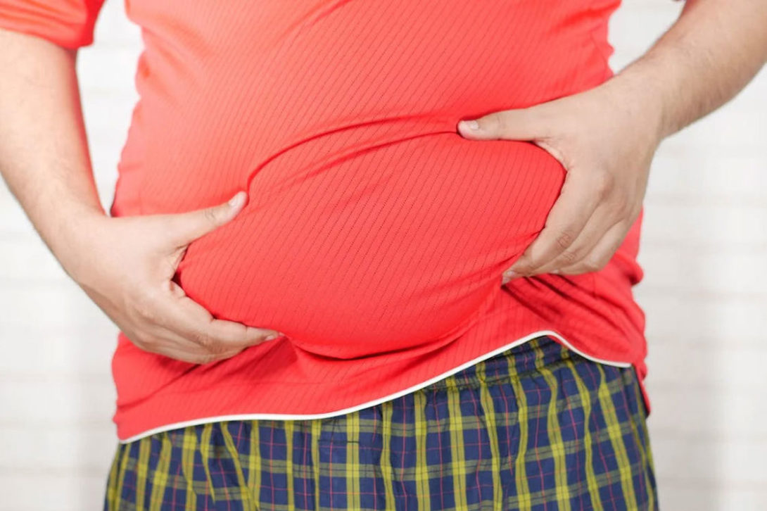 Person wearing a red shirt and holding their belly