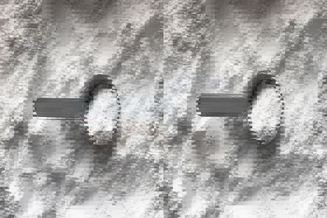 Gray scooper filled with white powder on top of white powder