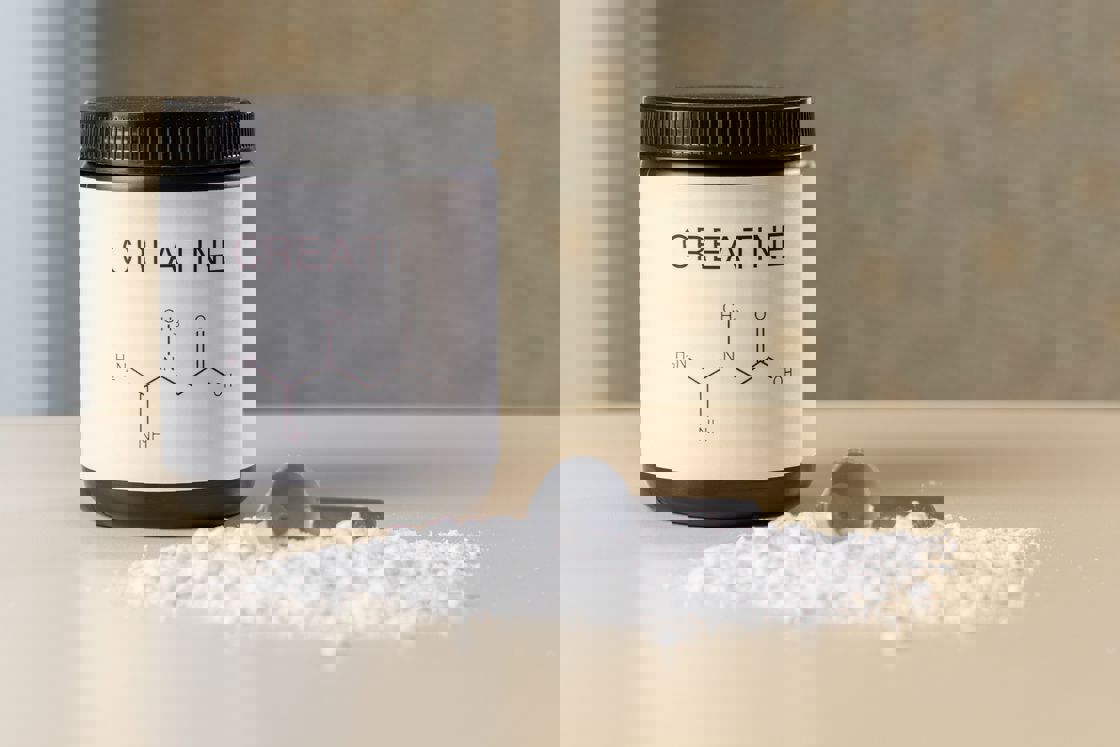 Creatine bottle with a scooper and white powder on the table