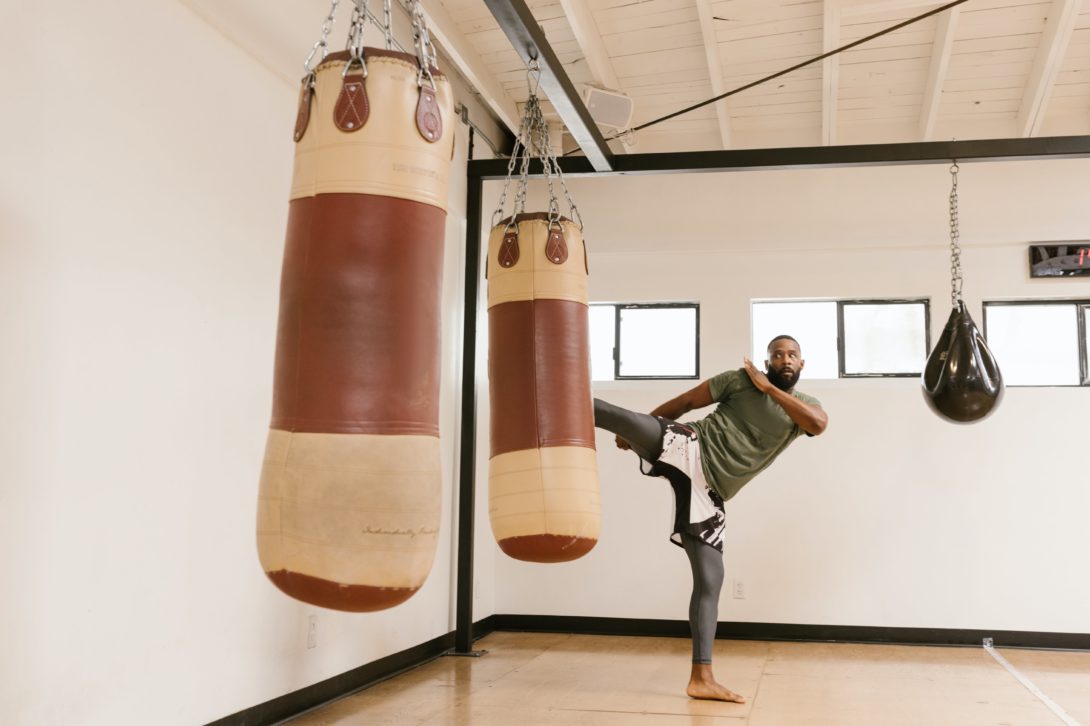 A man kicking a huge punching bag