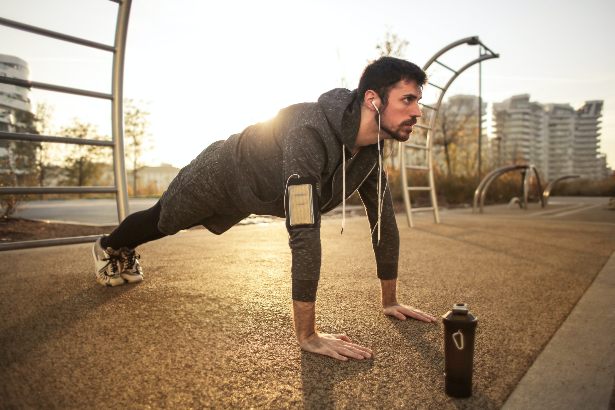 A man doing push ups outside with a water bottle in front of him