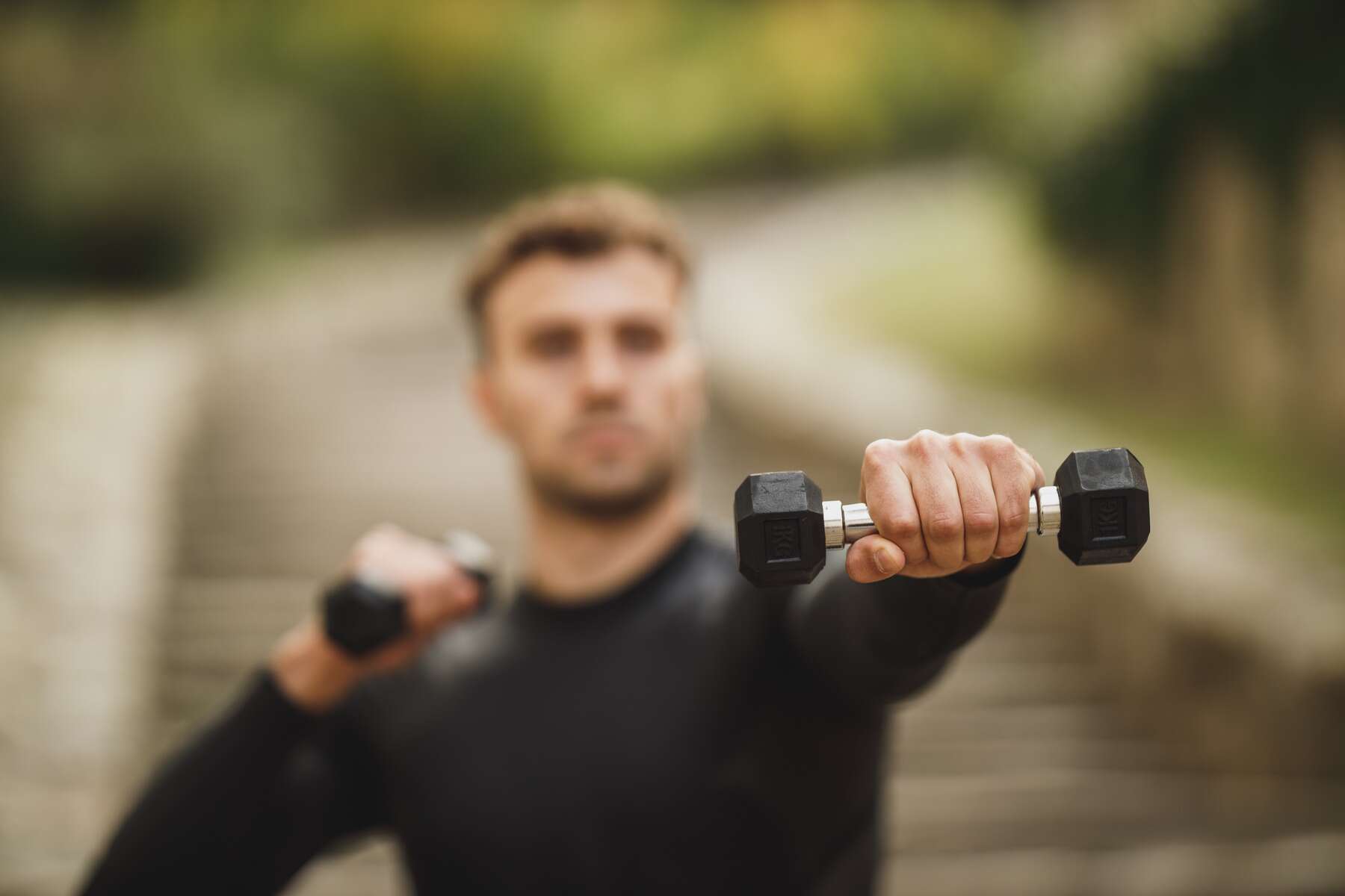 A man lifting dumbbells outside