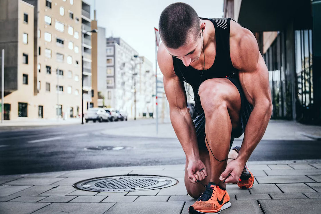 Man ties his shoelaces while walking on the sidewalk