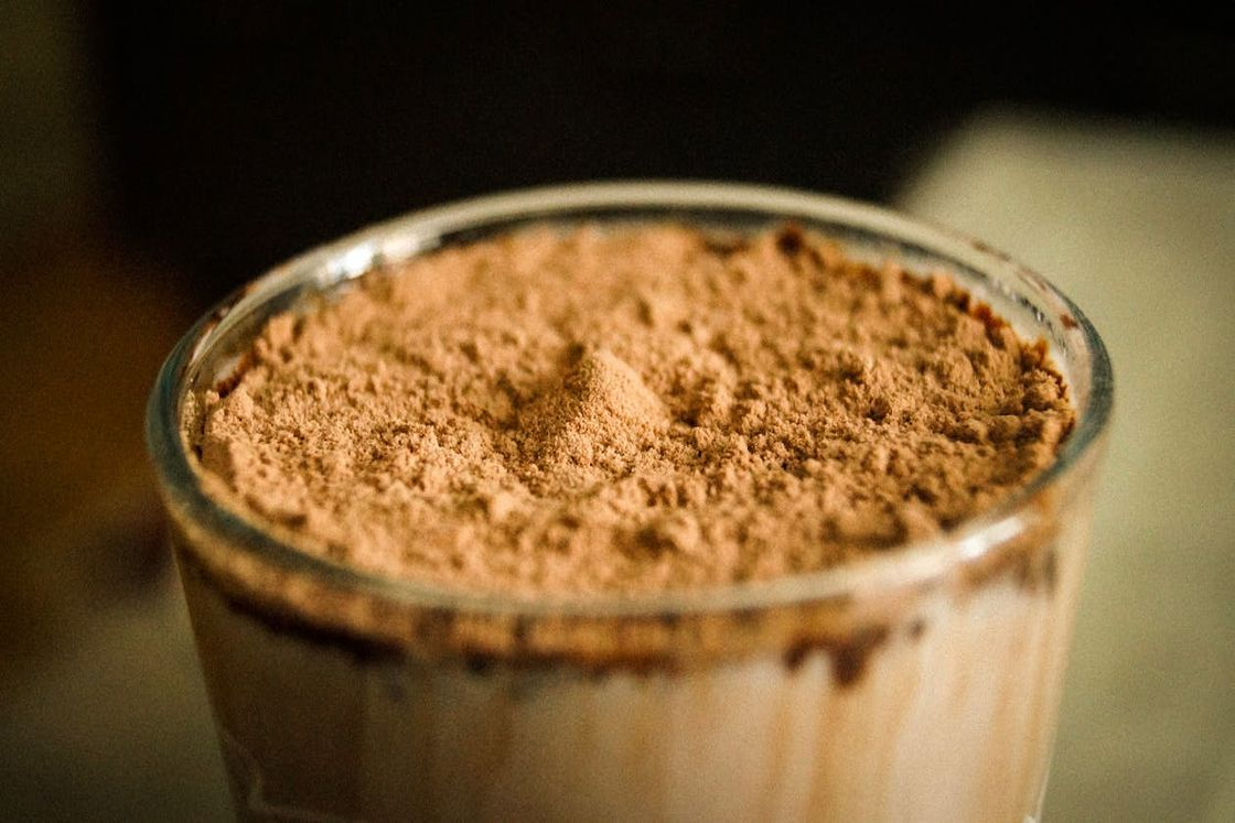 Chocolate powder on top of a glass of flavored protein smoothie