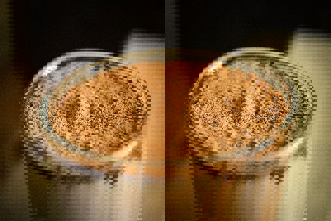 Chocolate powder on top of a glass of flavored protein smoothie