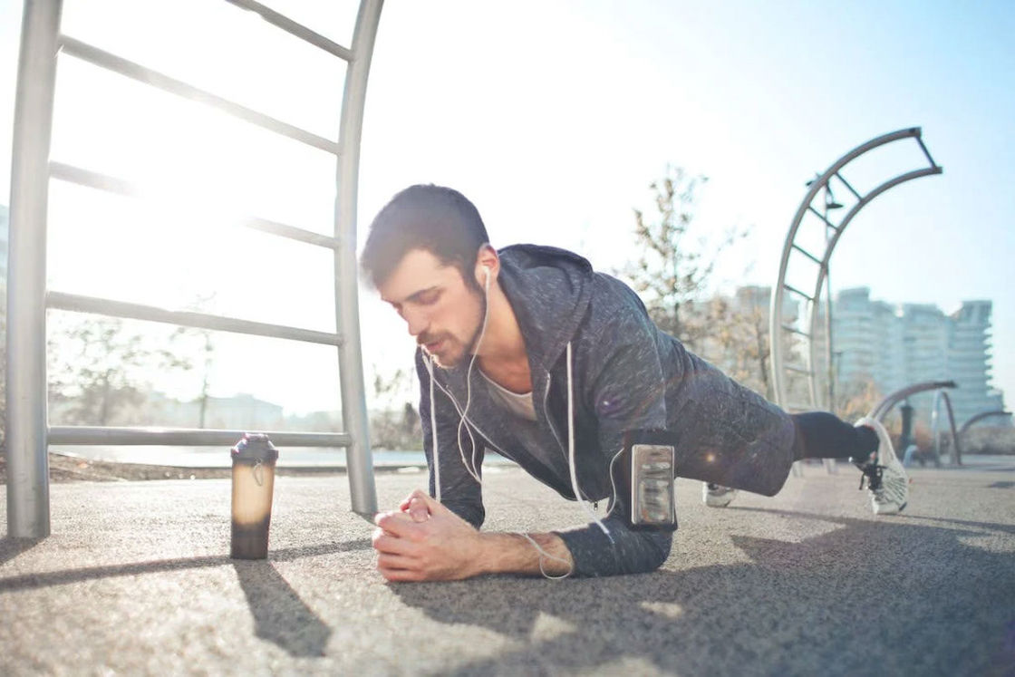 Man doing push up outdoors while his bottled drink is beside him