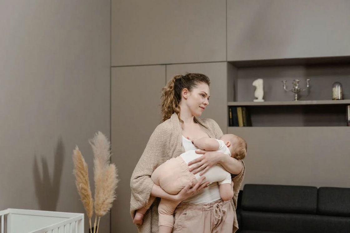 Woman breastfeeding her baby while standing in her living room