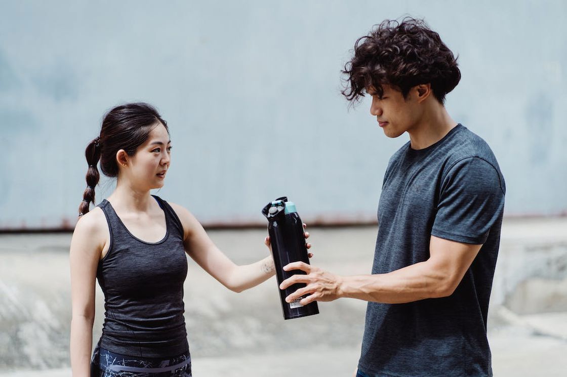 Man sharing his water tumbler to his girlfriend