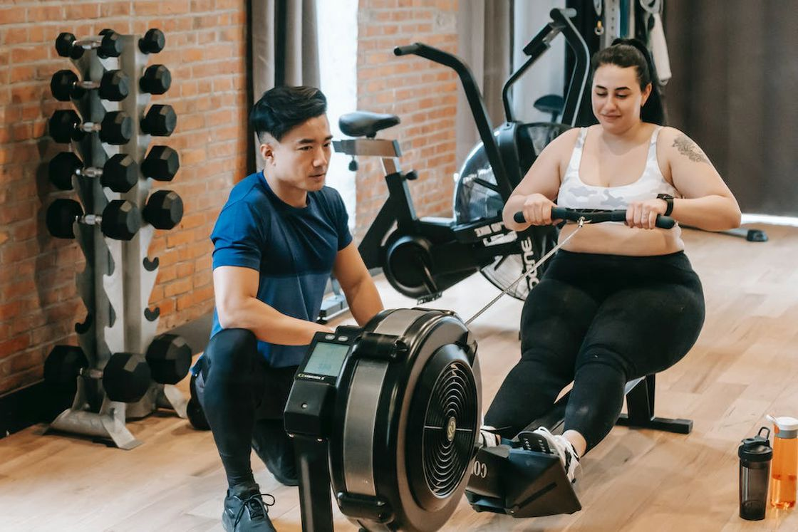 Trainer helping a woman with a rowing machine